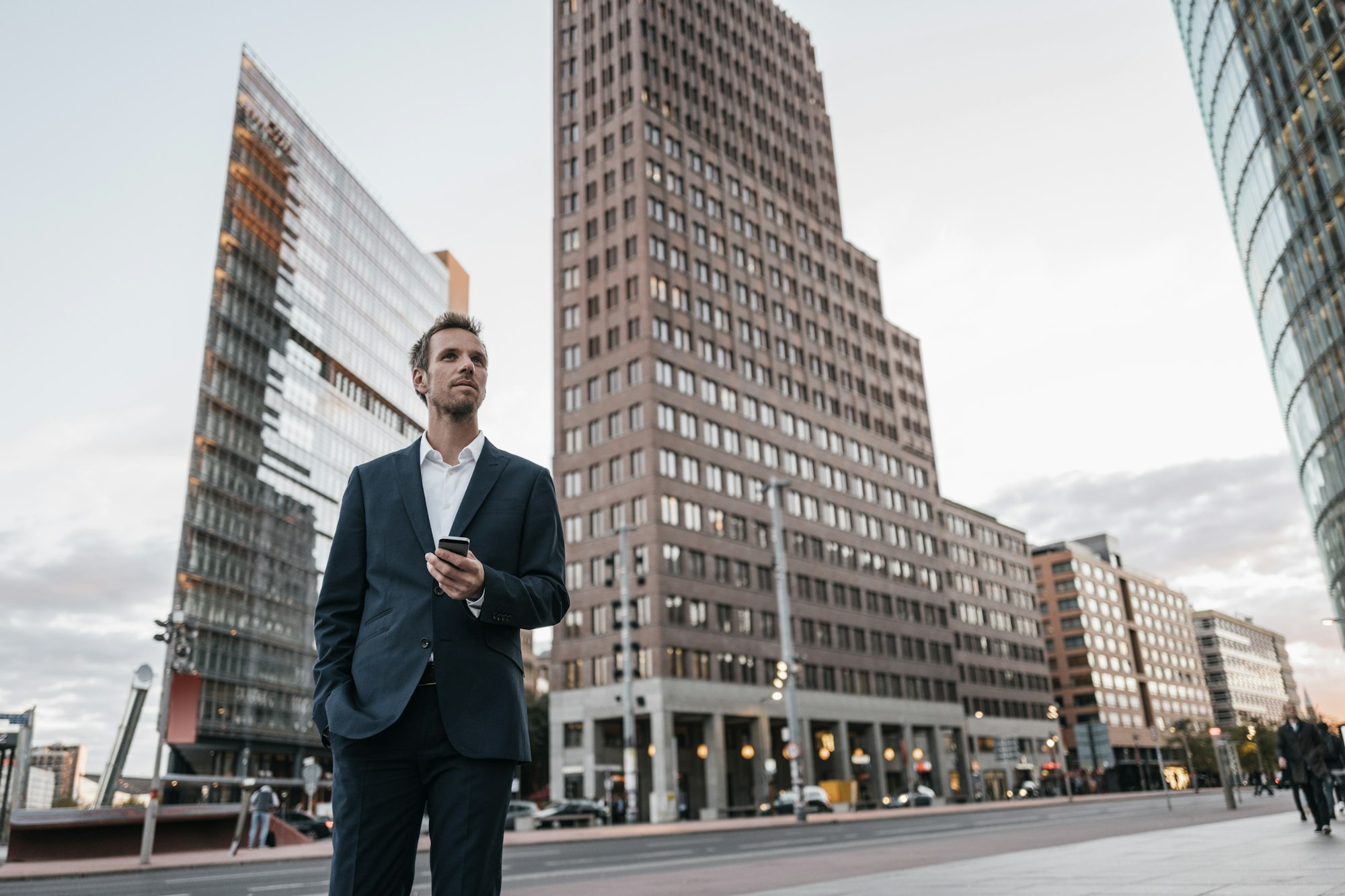 Germany, Berlin, businessman with smartphone standing at Potsdamer Platz