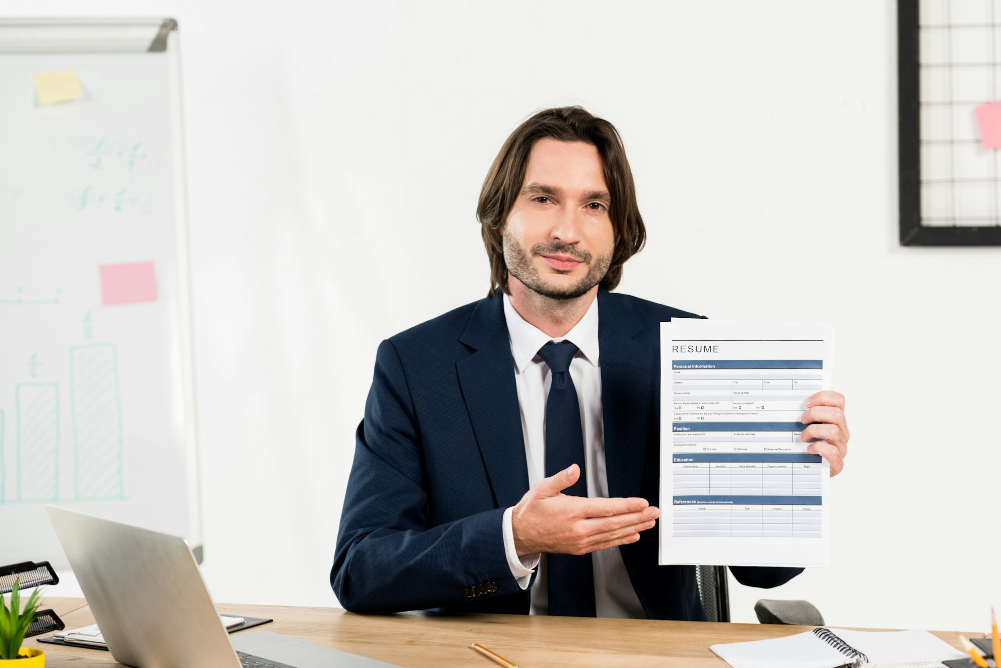 handsome recruiter gesturing while holding resume in office